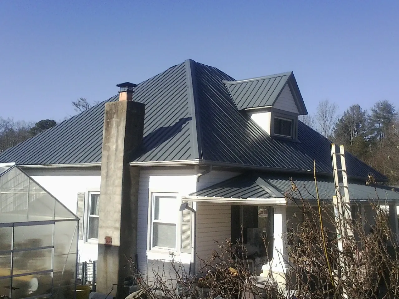 Dark blue standing seam metal roof on a white farmhouse with dormer — Slate & Tile Roof Repair by Roofing Brothers in Fort Jones