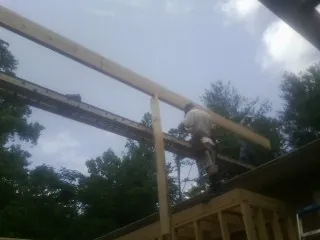 Carpenter setting a ridge beam over a new addition frame in Fort Jones