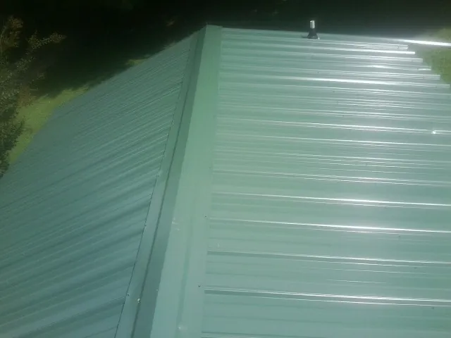 New green metal panels meeting at the ridge of a roof — Flat Roof Repair work by our crew in Fort Jones