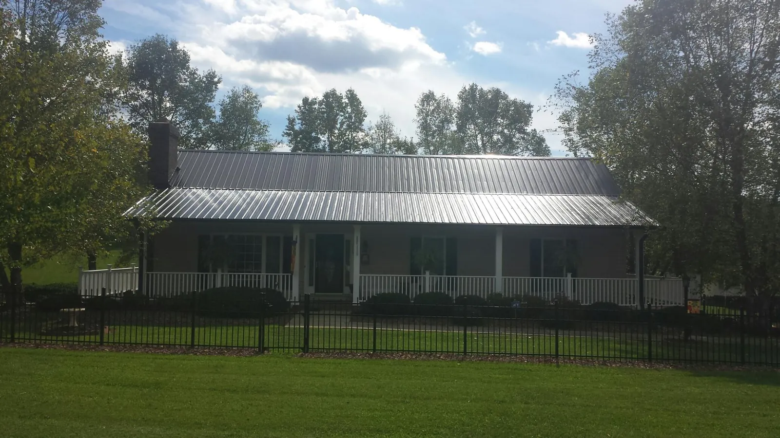 Gray metal roof on a brick ranch with a full width front porch — Gutter Guard Installation work by our crew in Fort Jones