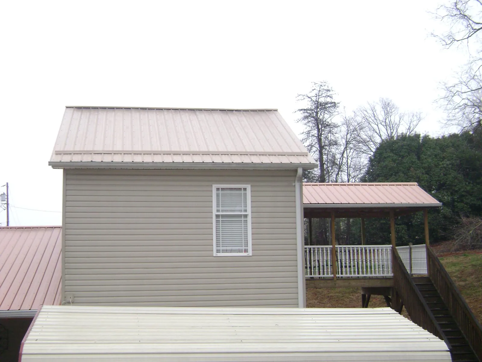 Tan metal roofs on a two story addition and attached porch, from a Roof Replacement job in Fort Jones