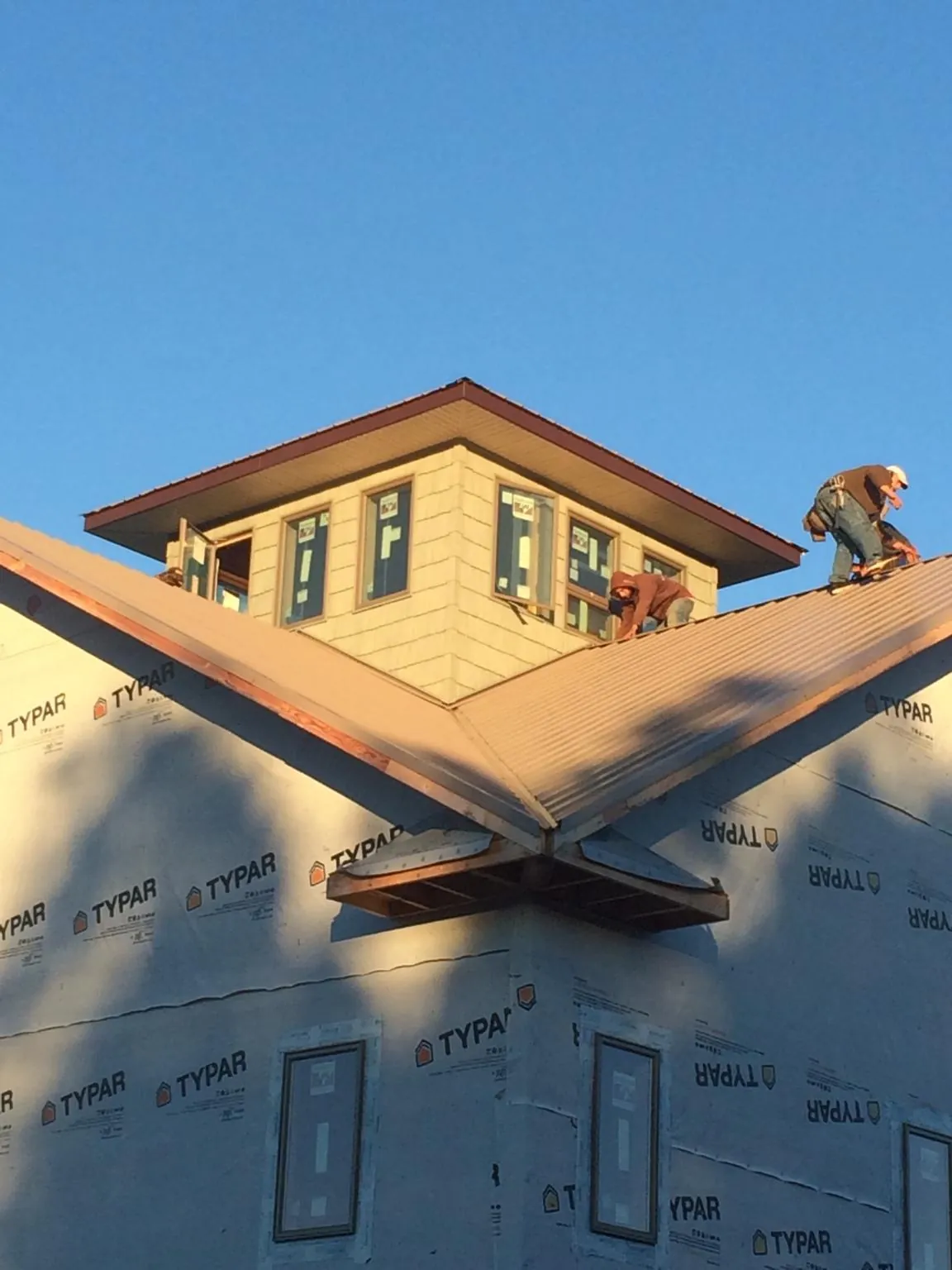 Roofers working around a rooftop cupola on a new metal roof at sunset — Roof Waterproofing in Fort Jones by Roofing Brothers